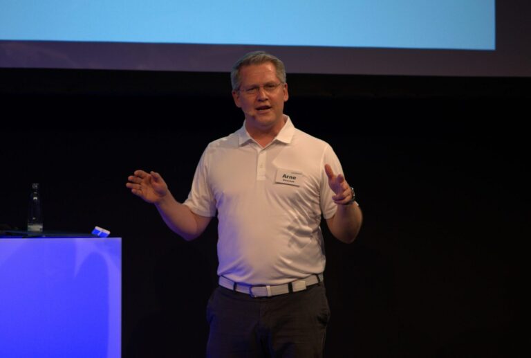 Arne Stoschek spricht im weißen Shirt auf der Bühne der DMEXCO